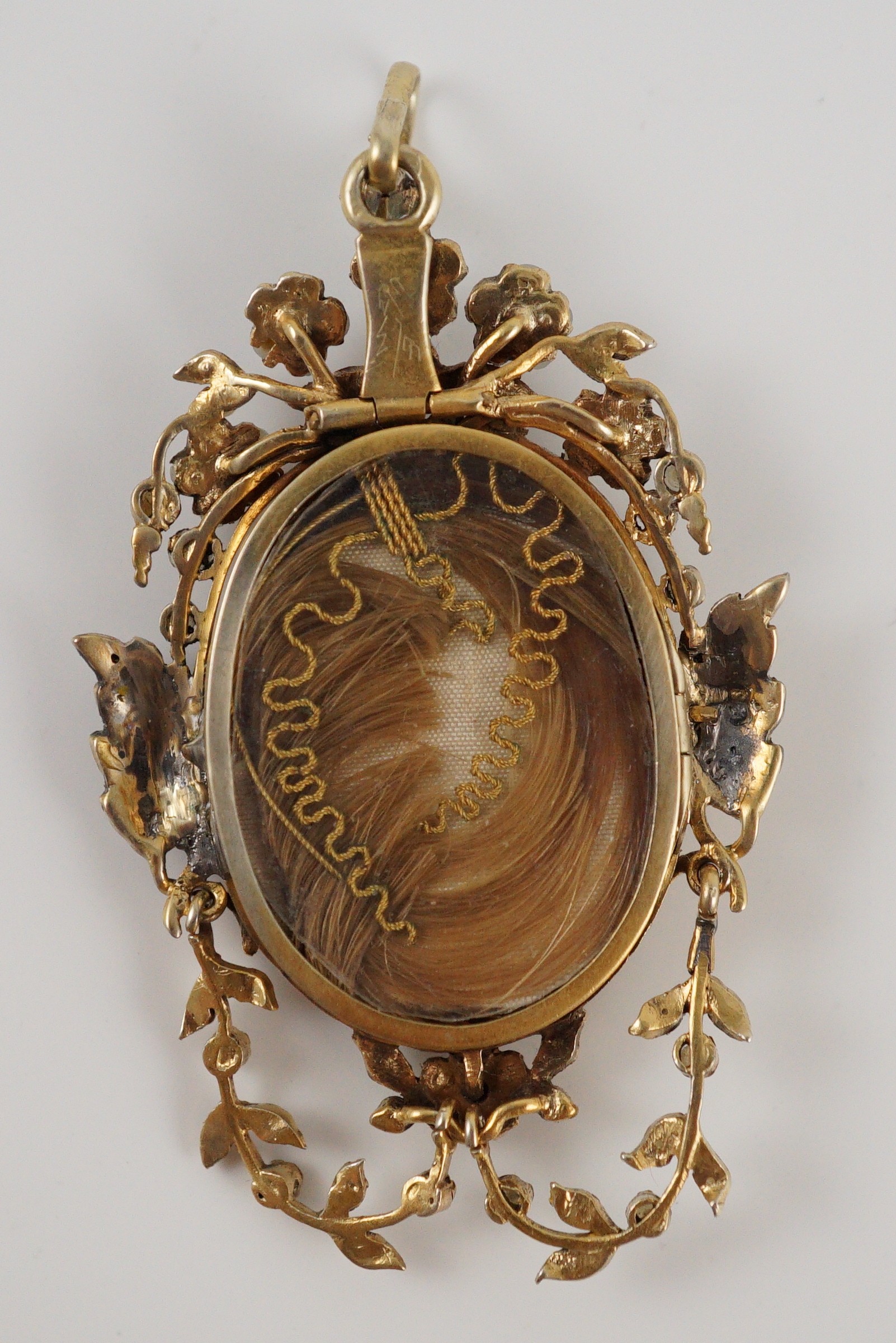 A Regency parcel gilt silver seed pearl and enamel set oval pendant, with inset ivory panel of a semi-clad figure with a lyre